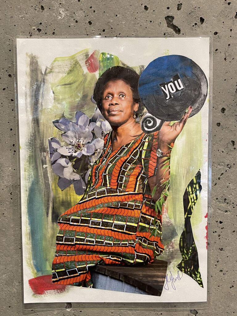 Die Collage von Daniela Hafner zeigt eine dunkelhäutige Frau mit einem farbigen Kleid. Die Frau hält in der rechten Hand eine runde Scheibe, auf der "you" zu lesen ist.