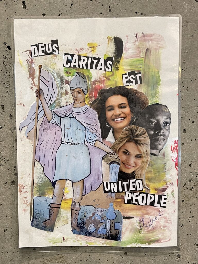 Auf der Collage sind der Heilige Florian und drei aus Zeitschriften ausgeschnittene Köpfe von Frauen zu sehen. Eine der Frauen ist blond, eine andere dunkelhaarig und eine hat eine dunkle Hautfarbe. Auf der Collage ist folgender Text zu lesen: "Deus Caritas est united people"